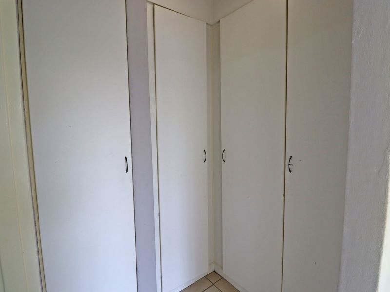A hallway area featuring white built-in cupboards providing ample storage space.