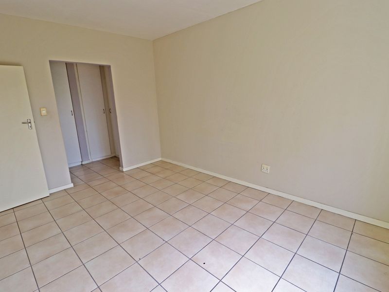 An empty bedroom featuring neutral wall paint, ceramic floor tiles, and built-in cupboard storage.