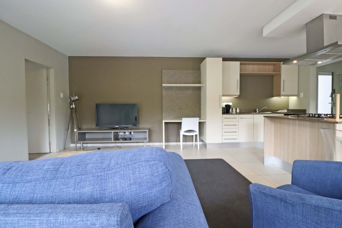 Open-plan living area featuring a modern kitchen with built-in cabinetry, stainless steel extractor fan, and a convenient integrated desk space.