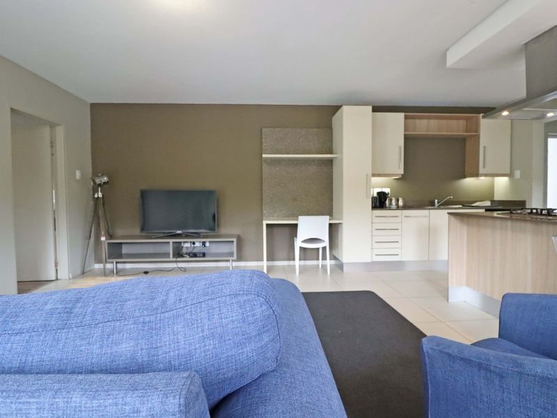 Open-plan living area featuring a modern kitchen with built-in cabinetry, stainless steel extractor fan, and a convenient integrated desk space.
