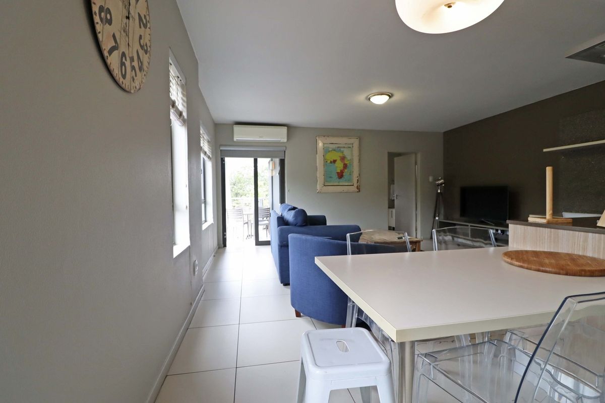 Open-plan living and dining area featuring tiled flooring, a split-system air conditioner, and direct access to an outdoor balcony through sliding glass doors.