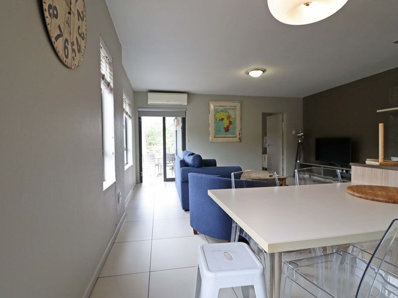 Open-plan living and dining area featuring tiled flooring, a split-system air conditioner, and direct access to an outdoor balcony through sliding glass doors.