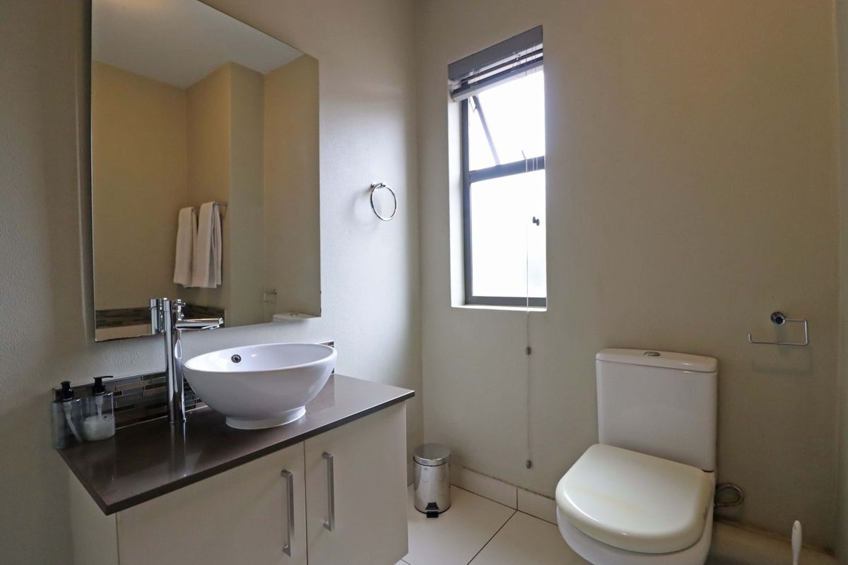 A clean and functional bathroom featuring a modern vessel sink on a vanity cabinet, a large wall mirror, and a standard toilet.