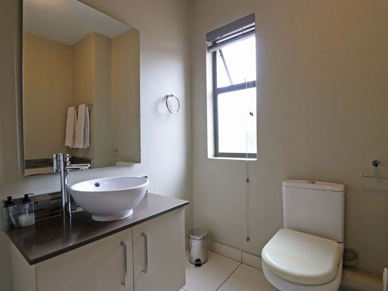 A clean and functional bathroom featuring a modern vessel sink on a vanity cabinet, a large wall mirror, and a standard toilet.