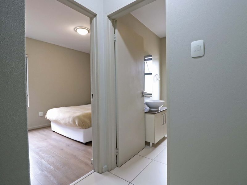 A view from the hallway looking into a bedroom and a bathroom featuring a modern vessel sink and vanity cabinet.