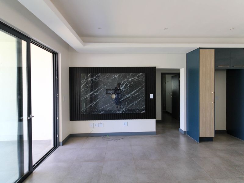 Modern open-plan living area featuring a marble-look feature wall, sleek cabinetry, and large sliding glass doors leading to an outdoor space.