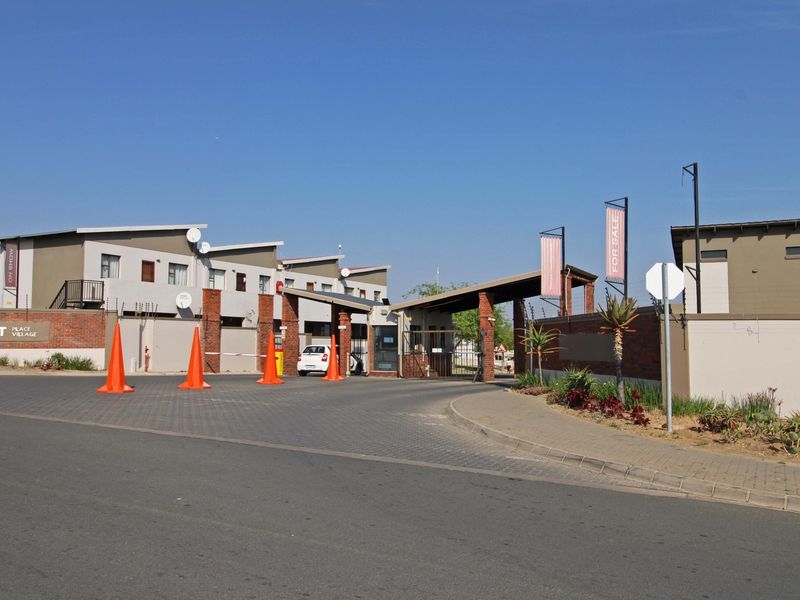 The entrance to Erset Place Village featuring a secure gated access point, brick boundary walls, and paved driveway.