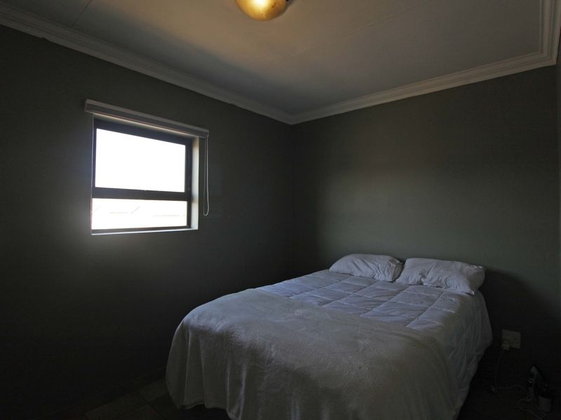 A simple bedroom featuring dark painted walls, a window, and ceiling cornice detailing.