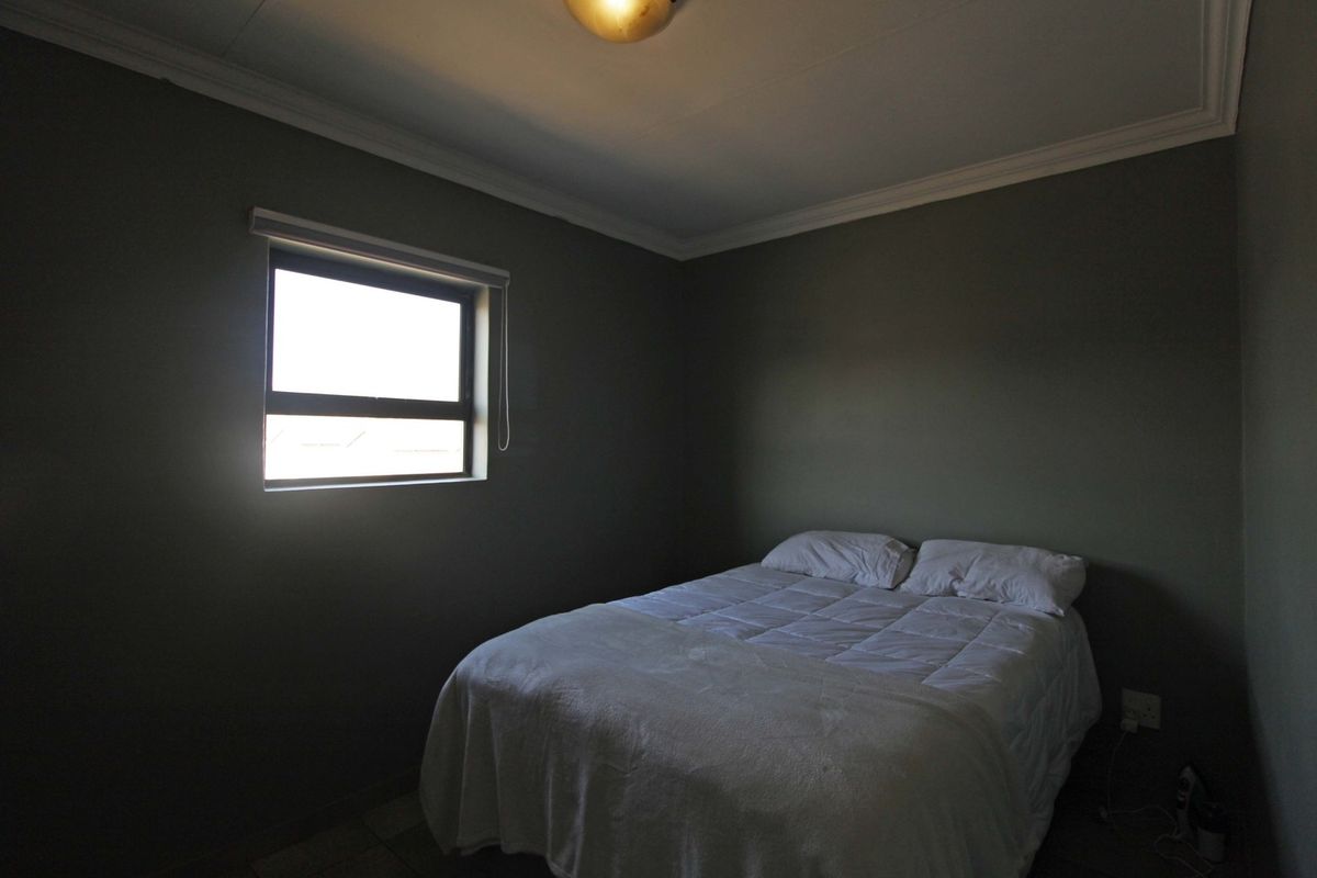 A simple bedroom featuring dark painted walls, a window, and ceiling cornice detailing.