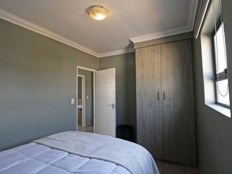 A well-maintained bedroom featuring neutral wall tones, built-in wooden cabinetry, and direct access to an adjoining bathroom.