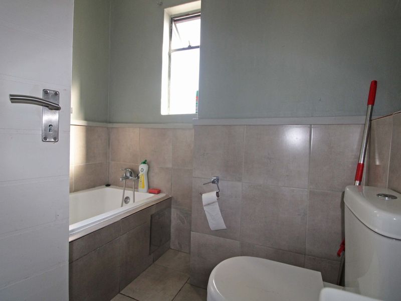 A functional bathroom featuring a built-in bathtub, tiled wall finishes, and a standard toilet, offering a clean and practical layout.