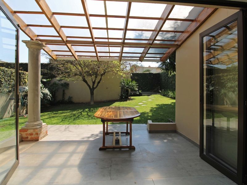Covered patio area featuring a timber pergola, stone column support, and large bi-fold doors opening onto a private garden.