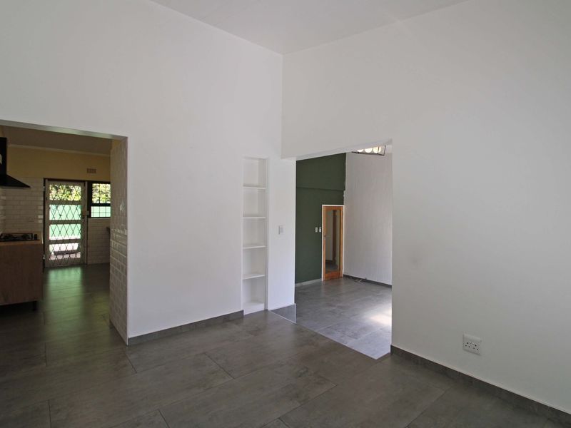 Open plan living area featuring modern tiled flooring, built-in shelving, and a view into the adjacent kitchen space.