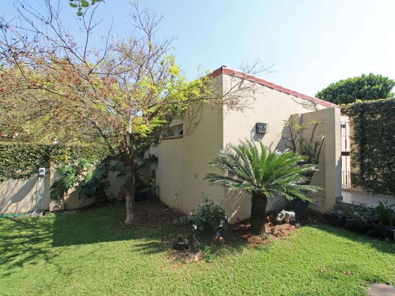 A view of the rear exterior of the townhouse, featuring a private garden area with established landscaping and boundary walls.