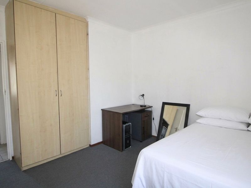 A functional bedroom featuring neutral walls, carpeted flooring, and a built-in wardrobe providing ample storage space.
