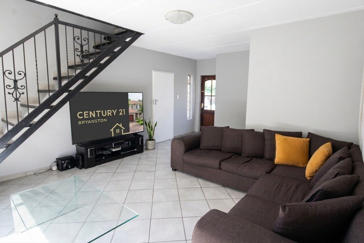 Open-plan living area featuring ceramic floor tiles and a wrought iron staircase leading to the upper level.