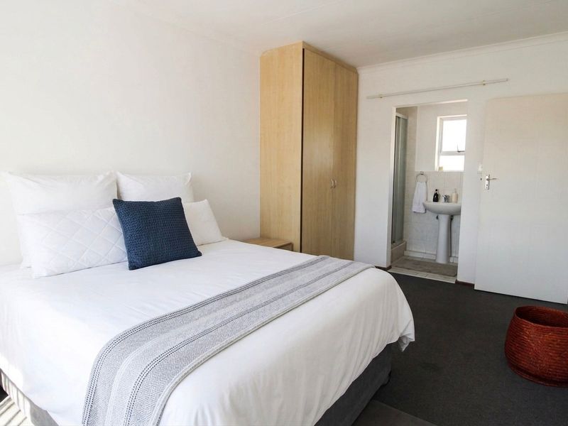 A bedroom featuring a built-in wardrobe and an attached en-suite bathroom with a pedestal basin and shower.