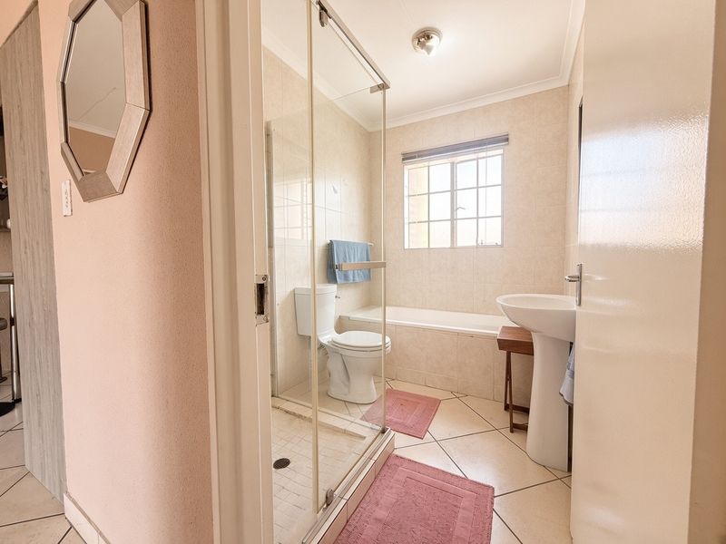 A functional bathroom featuring a pedestal basin, toilet, separate shower enclosure, and a built-in bathtub with tiled finishes throughout.