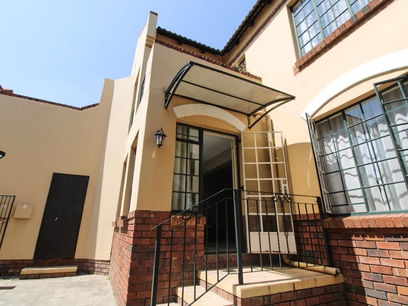 Front entrance of the apartment featuring a brick facade, security gate, and protective awning over the doorway.
