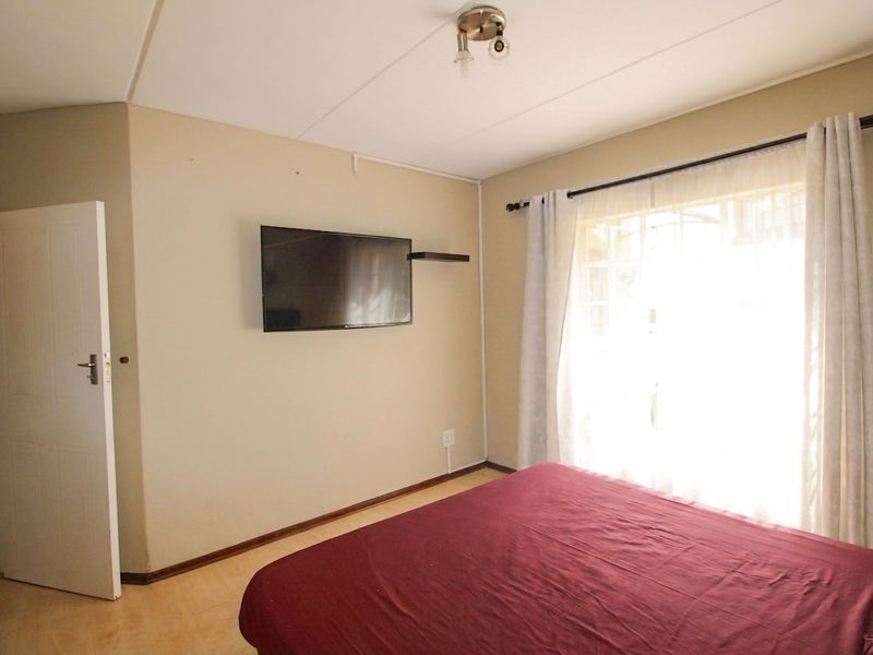 A functional bedroom featuring neutral wall finishes, a ceiling light fixture, and a window with a curtain rod.