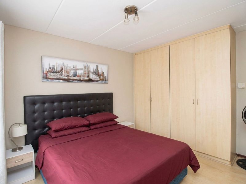 A functional bedroom featuring light-toned laminate flooring and a large built-in wardrobe providing ample storage space.
