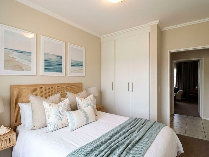 A well-maintained bedroom featuring neutral walls, crown molding, carpeted flooring, and a spacious built-in wardrobe.