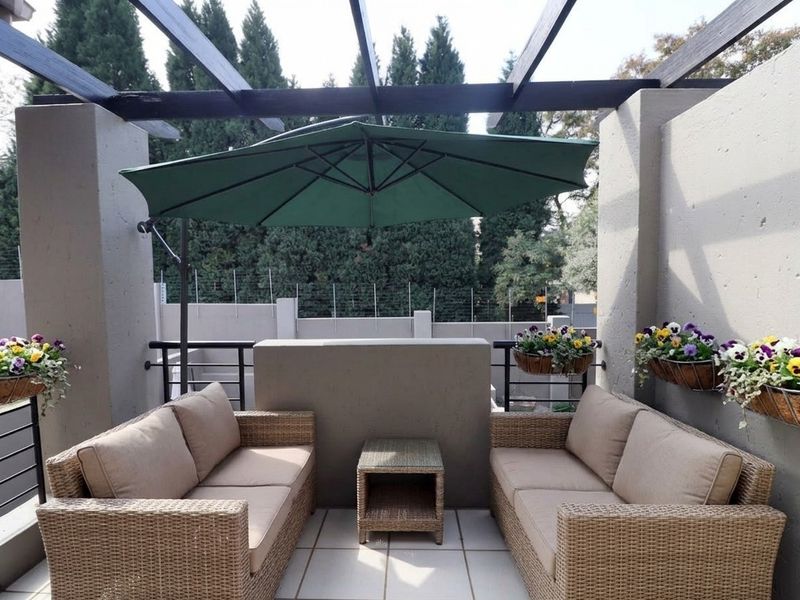 A covered balcony featuring a timber pergola, tiled flooring, and metal balustrades, providing a comfortable outdoor seating area.