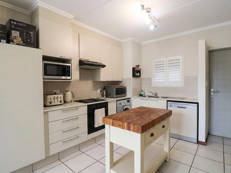 A functional kitchen featuring built-in cabinetry, integrated appliances, a hob, oven, extractor fan, and a double sink with tiled flooring.