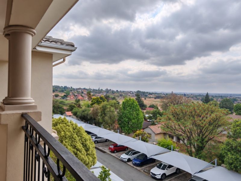 Elevated view from a balcony overlooking a residential neighborhood with covered parking bays and surrounding greenery.
