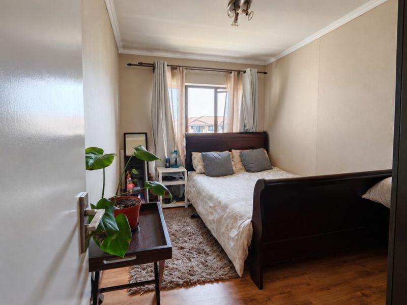 A cozy bedroom featuring laminate flooring, ceiling coving, and a window that allows natural light into the space.