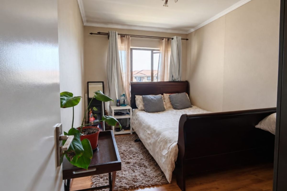 A cozy bedroom featuring laminate flooring, ceiling coving, and a window that allows natural light into the space.