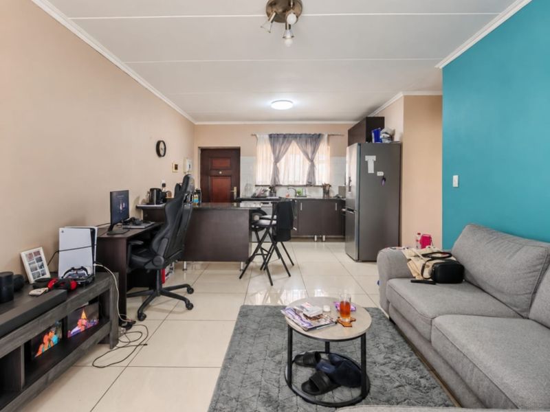 Open-plan living area featuring a combined kitchen and lounge space with tiled flooring and neutral wall finishes.