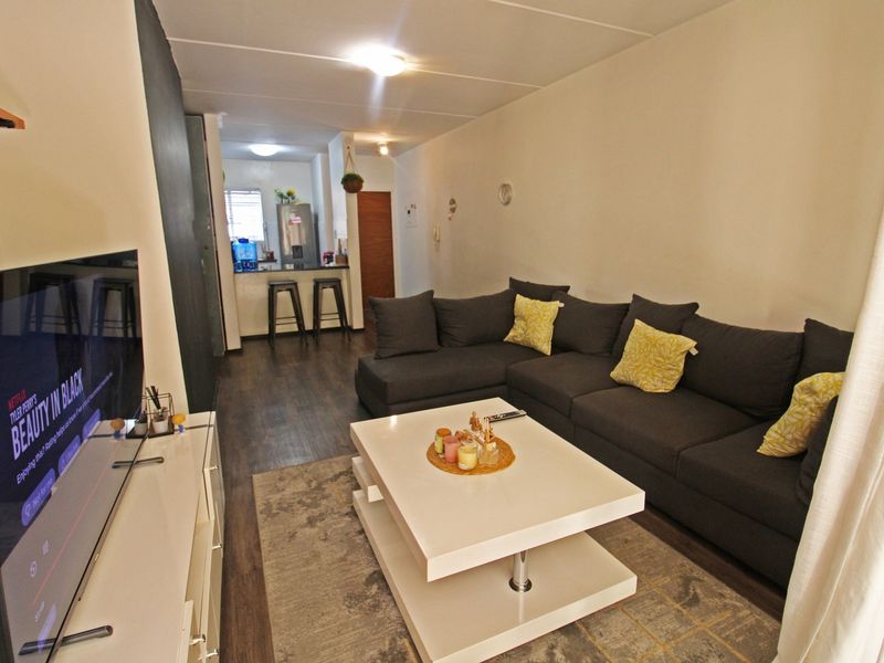 Open-plan living area featuring dark laminate flooring and a breakfast counter connecting to the kitchen space.