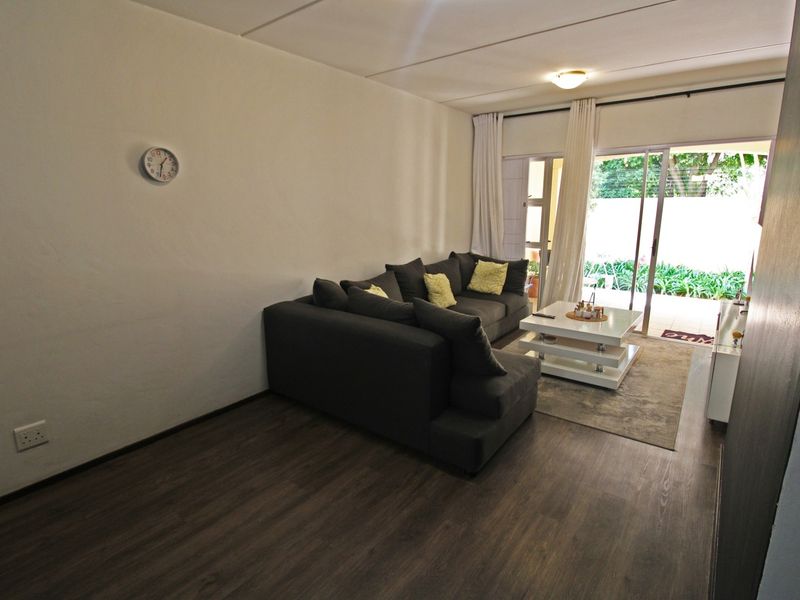 A living room featuring dark laminate flooring and a sliding glass door providing access to an outdoor patio area.