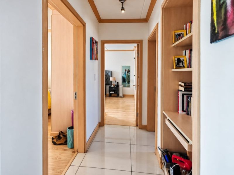A bright hallway featuring tiled flooring, wooden door frames, and integrated built-in shelving, providing access to adjacent rooms.
