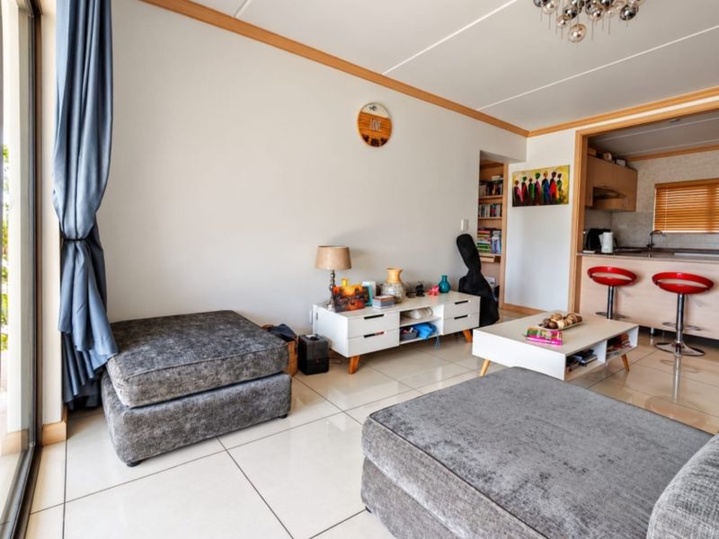 Open-plan living area featuring polished tile flooring, a breakfast bar connecting to the kitchen, and direct access to an outdoor space via sliding doors.