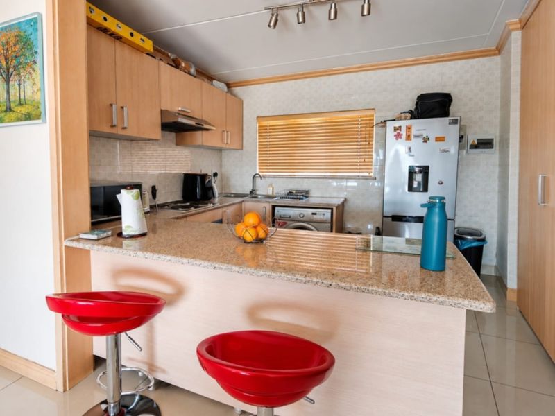 A functional kitchen featuring granite countertops, light wood cabinetry, and tiled flooring, offering a practical layout with integrated appliances and breakfast bar seating.