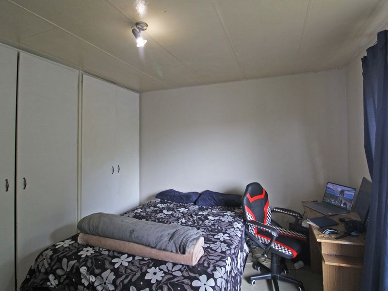 A functional bedroom featuring built-in cupboards and neutral finishes, offering a practical space for rest or study.