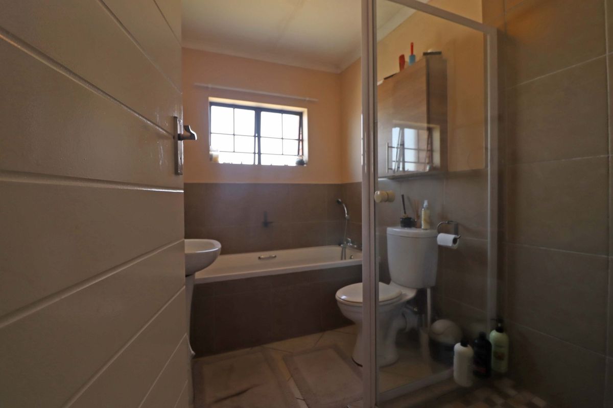 A functional bathroom featuring a bathtub, pedestal basin, toilet, and a separate shower enclosure with tiled finishes throughout.