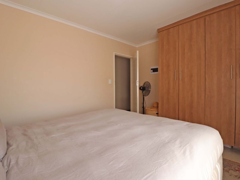 A bedroom featuring neutral wall tones and a large, wood-finish built-in wardrobe providing ample storage space.