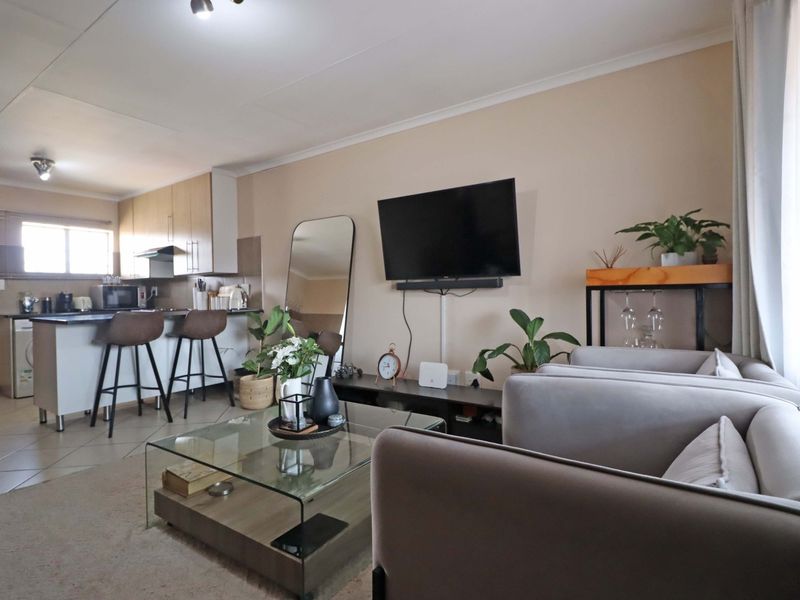 An open-plan living area featuring a modern kitchen with island seating, tiled floors, and neutral wall finishes, creating a functional and cohesive living space.
