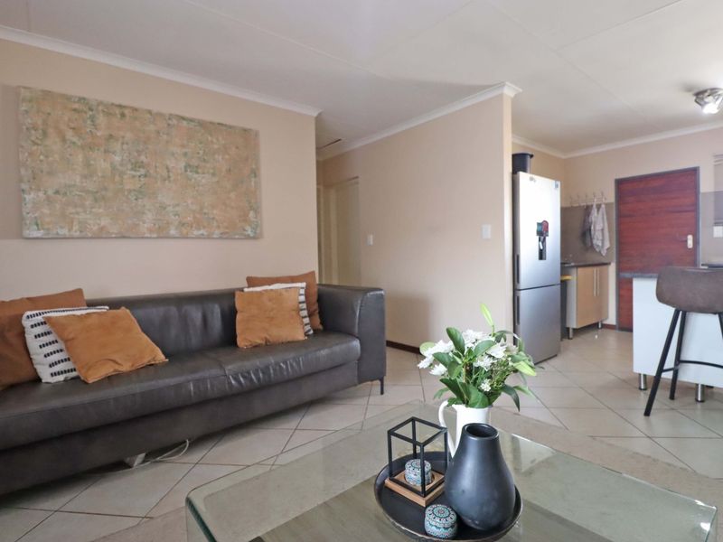 Open-plan living area featuring tiled flooring and a functional kitchen with a breakfast island, creating a cohesive and practical living space.