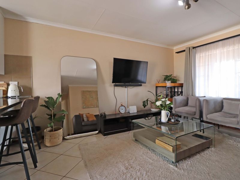 An open-plan living area featuring tiled flooring, integrated kitchen cabinetry, and a neutral color palette, providing a functional and connected living space.