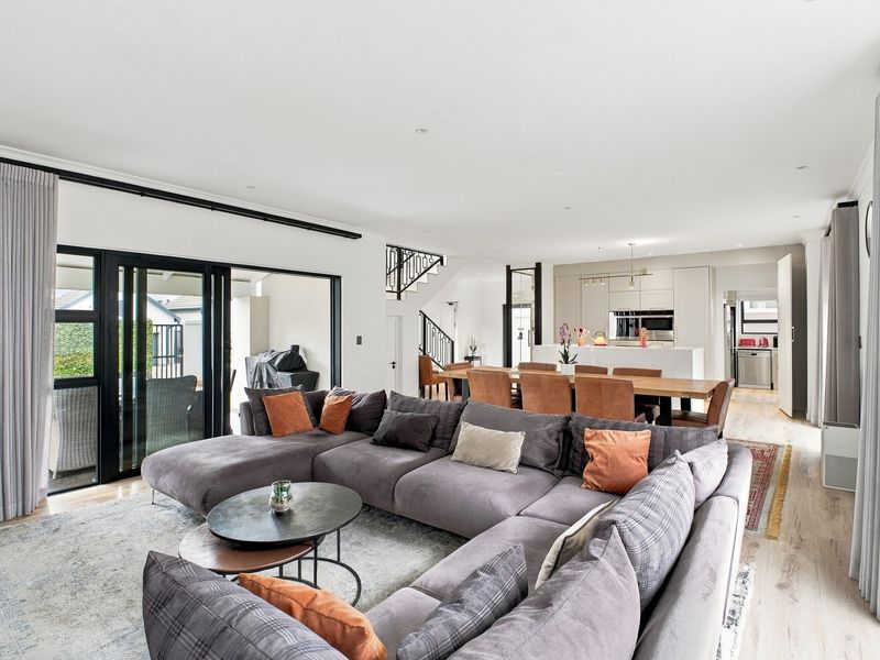 Spacious open-plan living, dining, and kitchen area featuring modern finishes, recessed lighting, and large sliding doors leading to the outdoor patio.