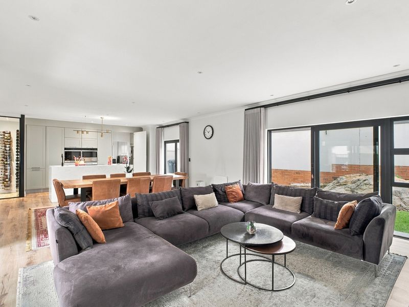 Spacious open-plan living, dining, and kitchen area featuring modern cabinetry, integrated appliances, and large sliding glass doors leading to the garden.