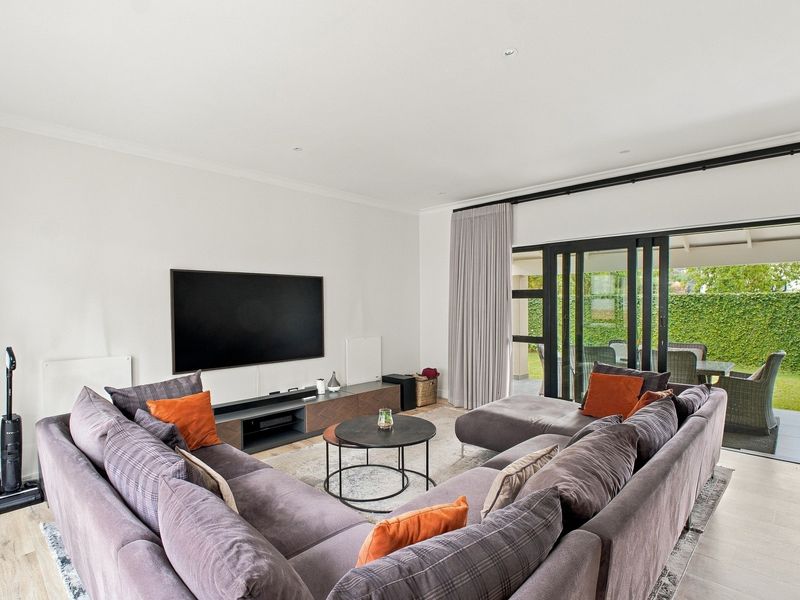 Spacious living room featuring tiled flooring, recessed lighting, and large sliding glass doors providing seamless access to the outdoor patio and garden area.
