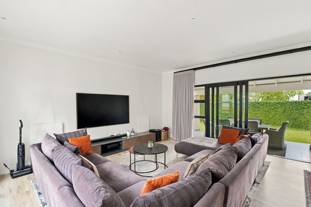 Spacious living room featuring tiled flooring, recessed lighting, and large sliding glass doors providing seamless access to the outdoor patio and garden area.
