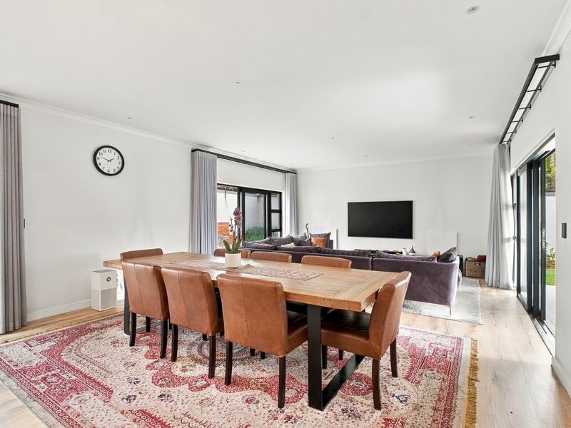 Spacious open-plan living and dining area featuring light laminate flooring, recessed lighting, and large sliding glass doors providing access to the outdoor space.