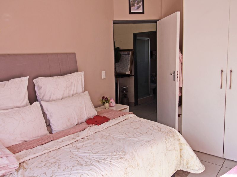 A bedroom featuring tiled flooring and a built-in wardrobe, with an adjoining bathroom visible through the open doorway.