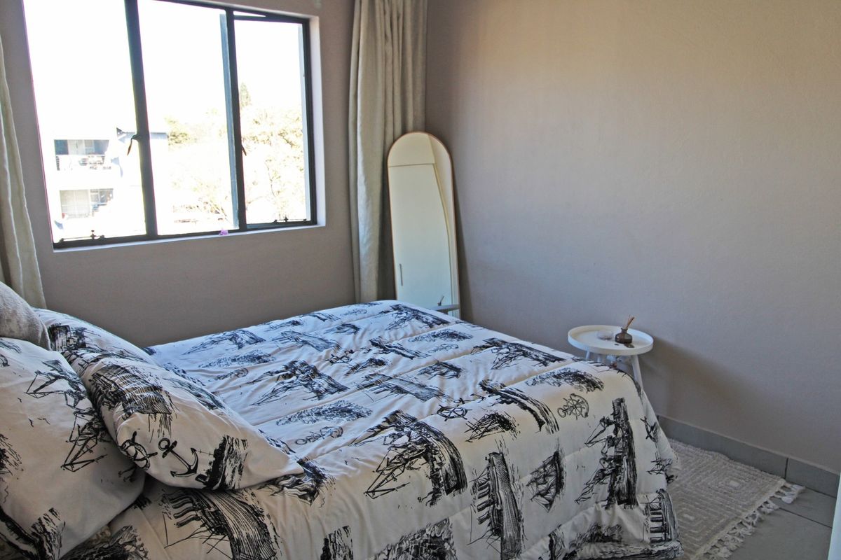A functional bedroom featuring tiled flooring and a large window that allows for natural light.